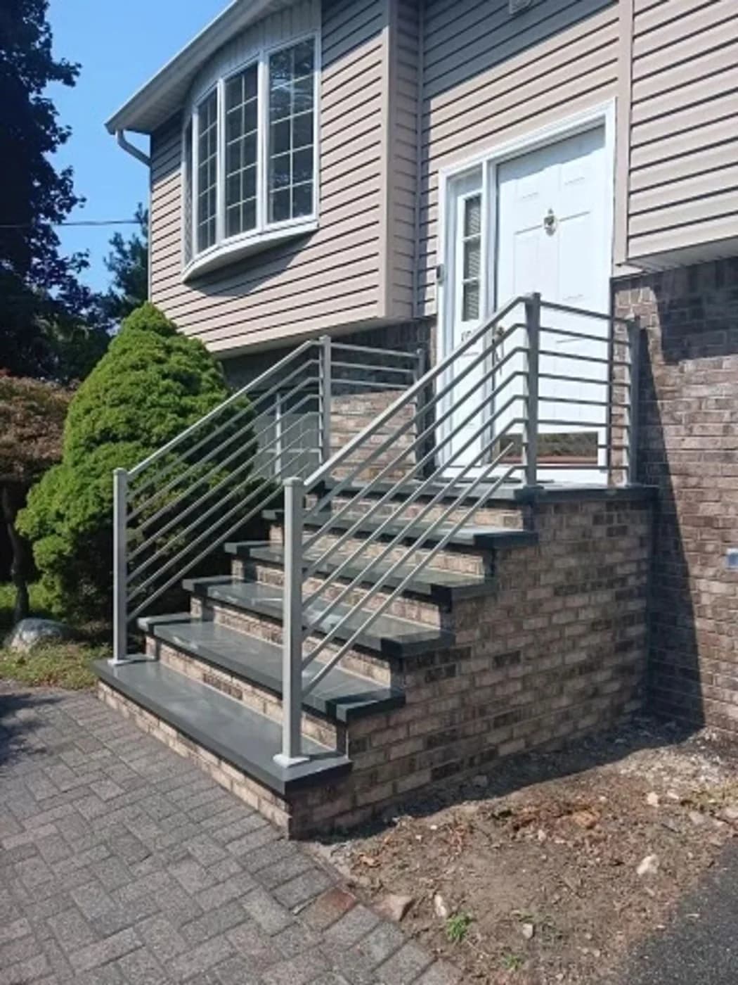 Front masonry staircase with dark treads and horizontal metal railings