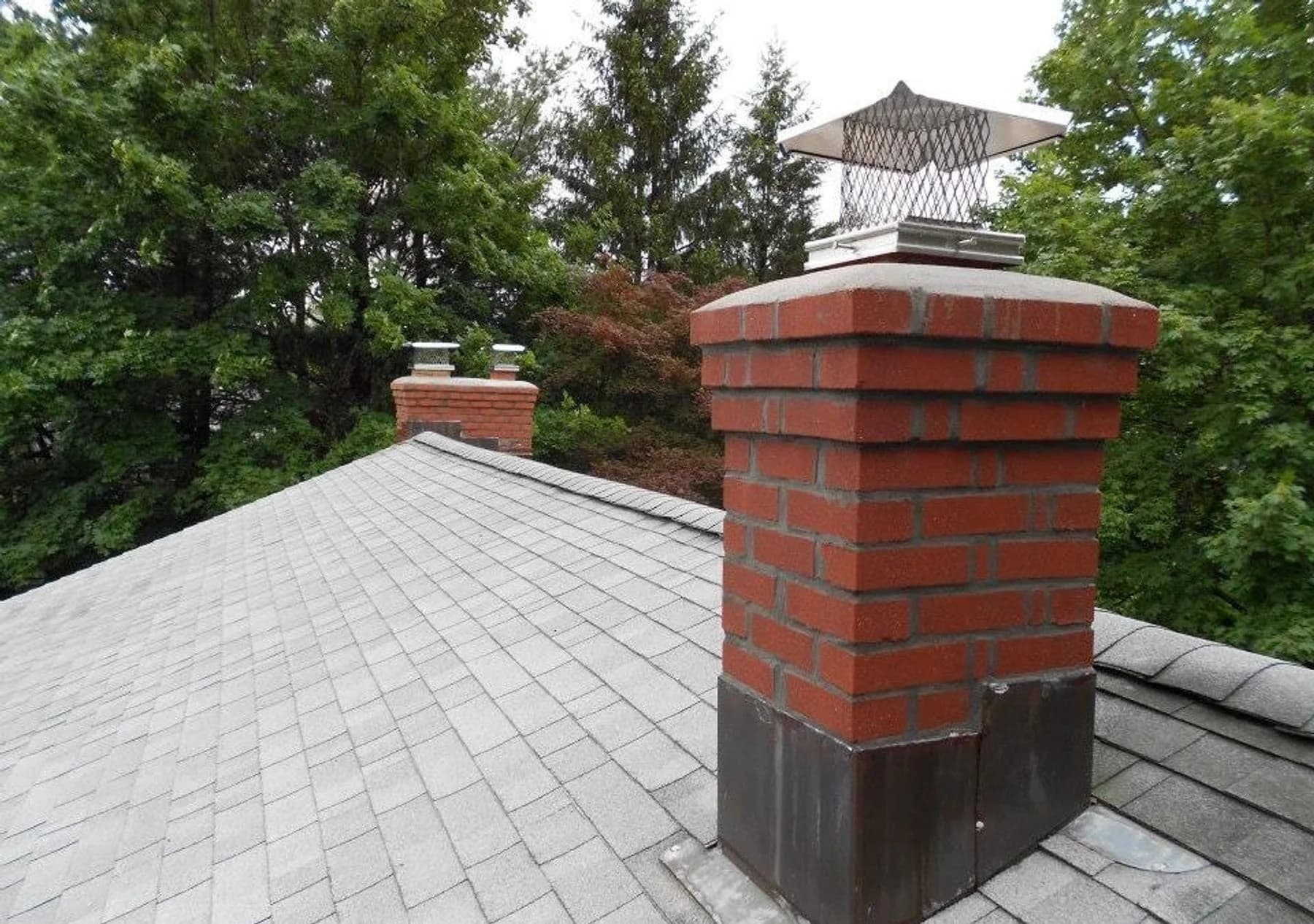 Paired red-brick chimneys with metal caps above the gray roof