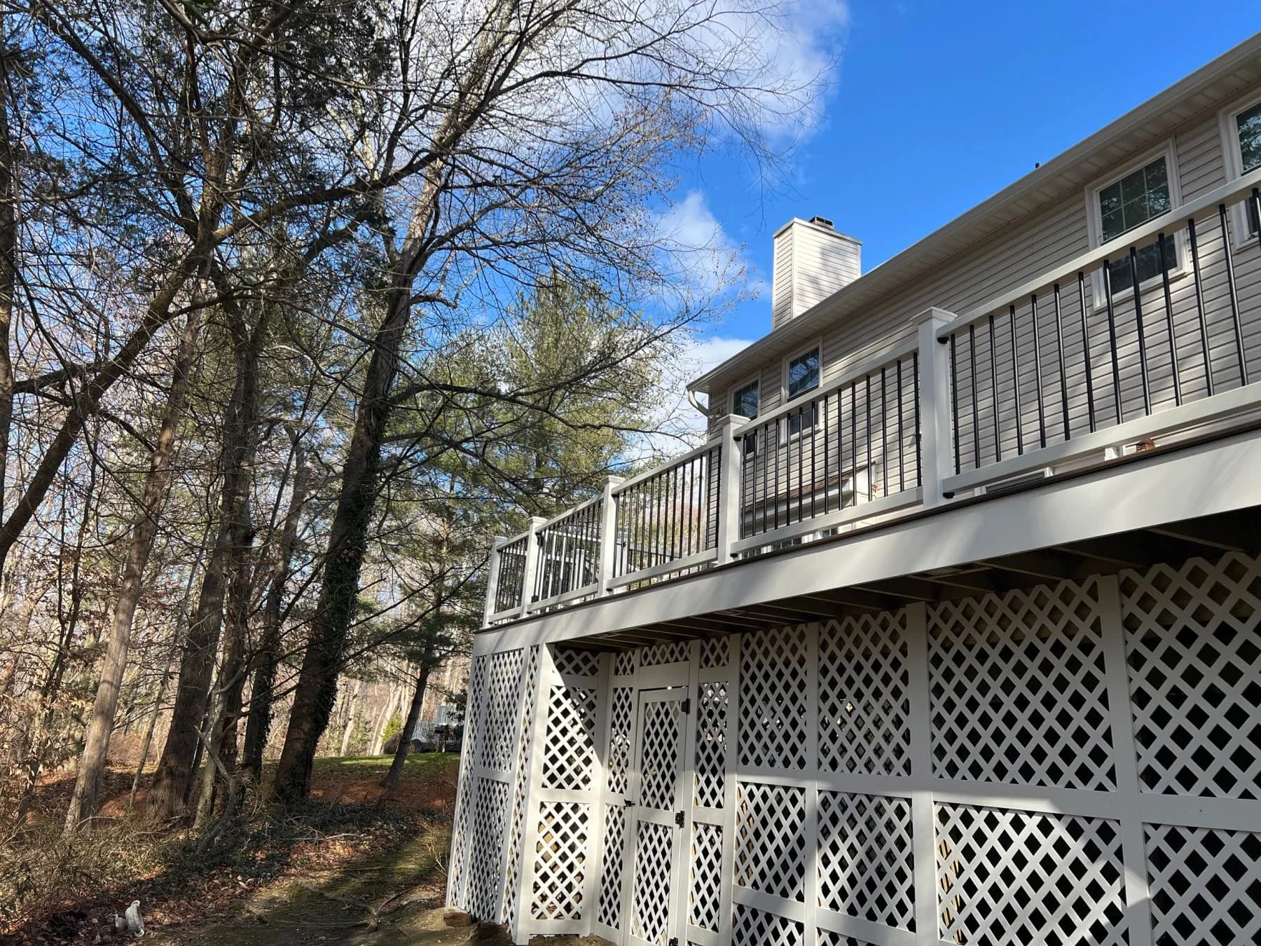 Rear view of the same beige home and raised deck with lattice beneath