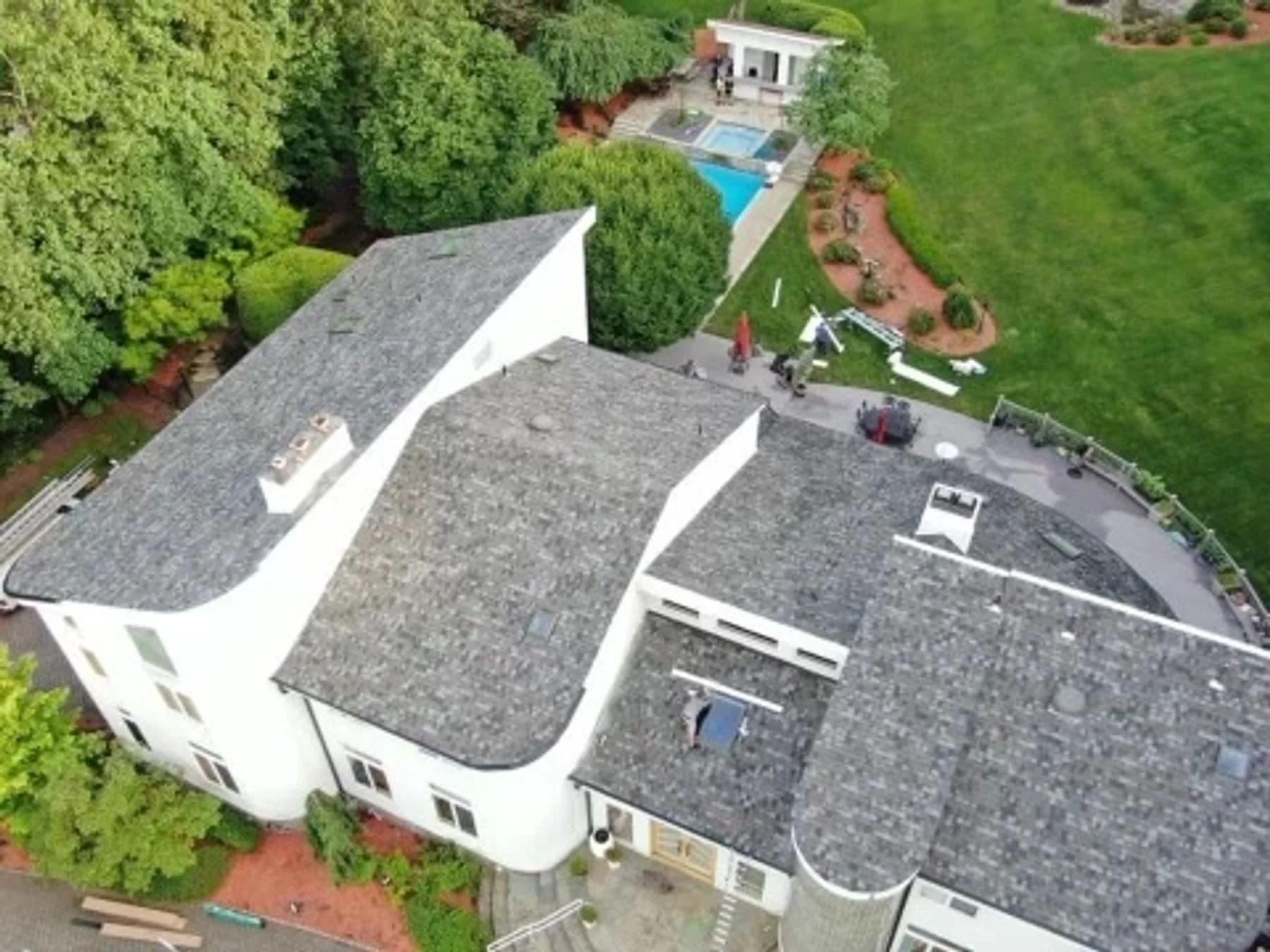Aerial view of the white contemporary home’s gray shingle roof and curved eaves