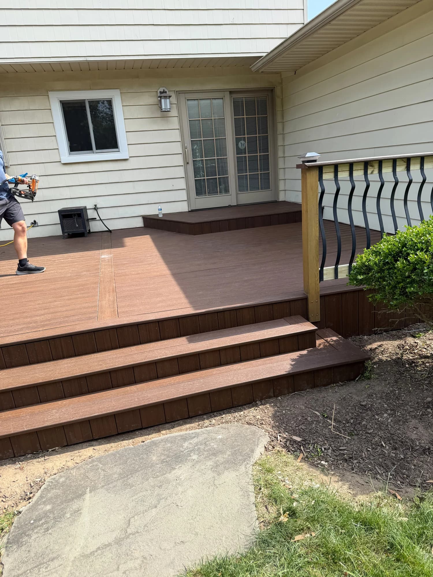 Brown deck surface and wide stair treads with work continuing near the patio doors