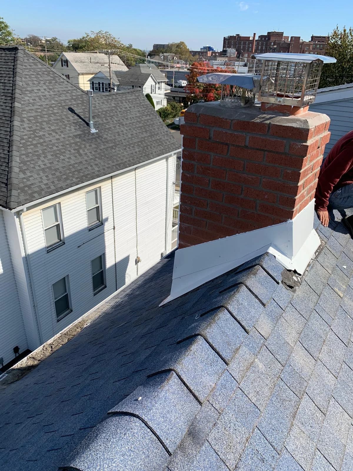 Roof-level view of the capped red-brick chimney and white roof flashing