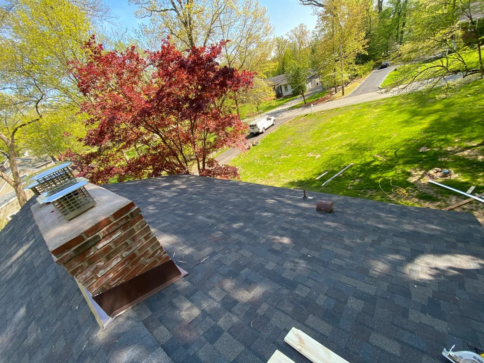 Gray shingle roof and brick chimney overlooking the split-level front yard