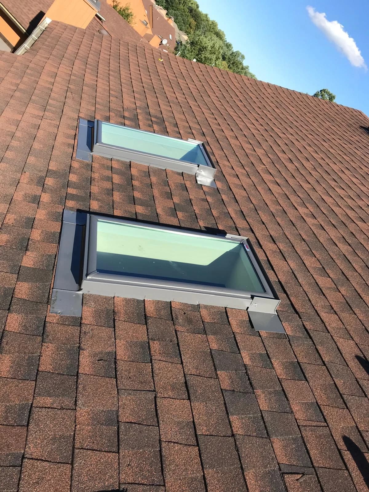 Two clear rectangular skylights set into the brown shingle roof