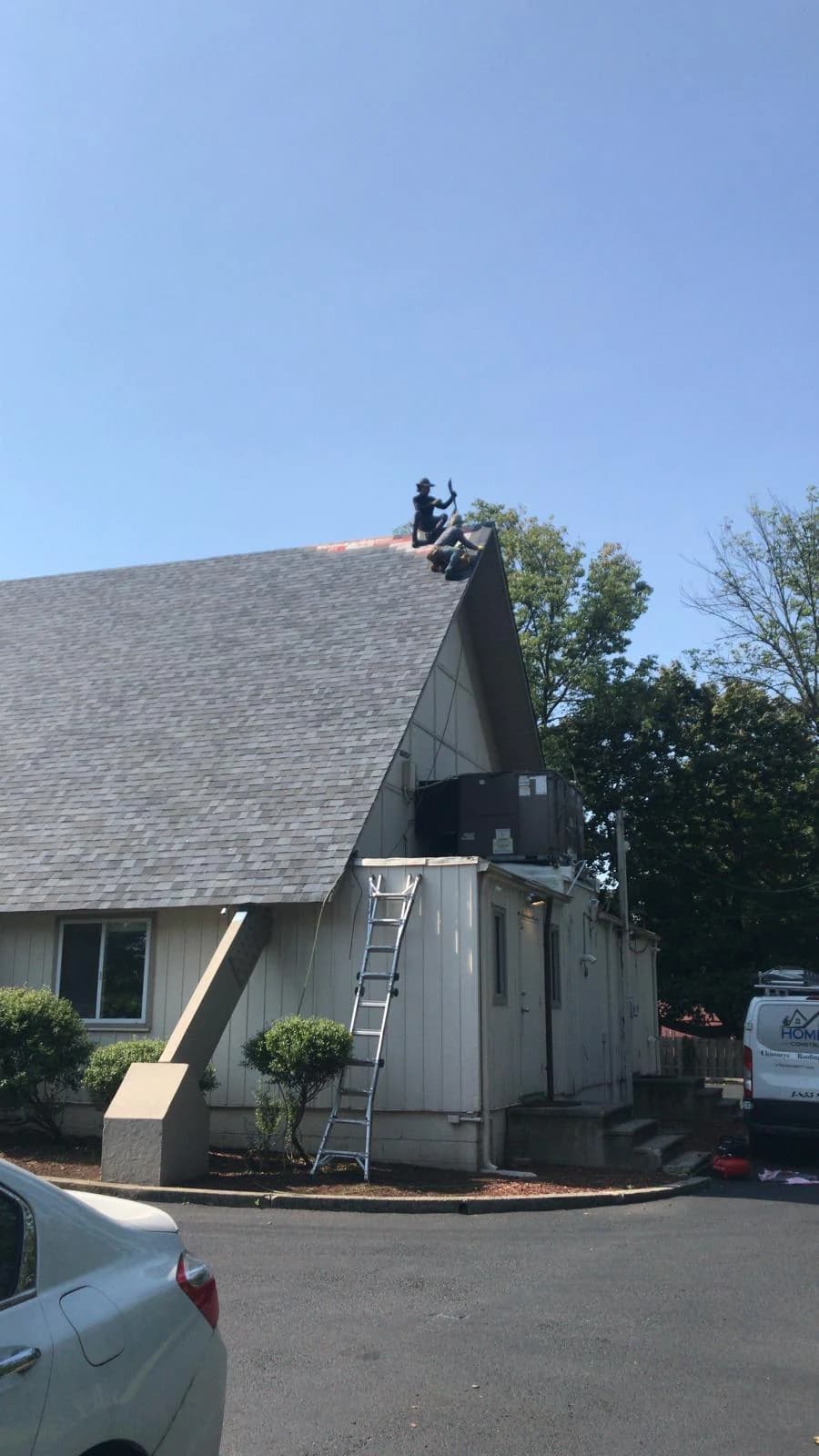Installed gray shingles on the commercial gable while crew work continues at the ridge