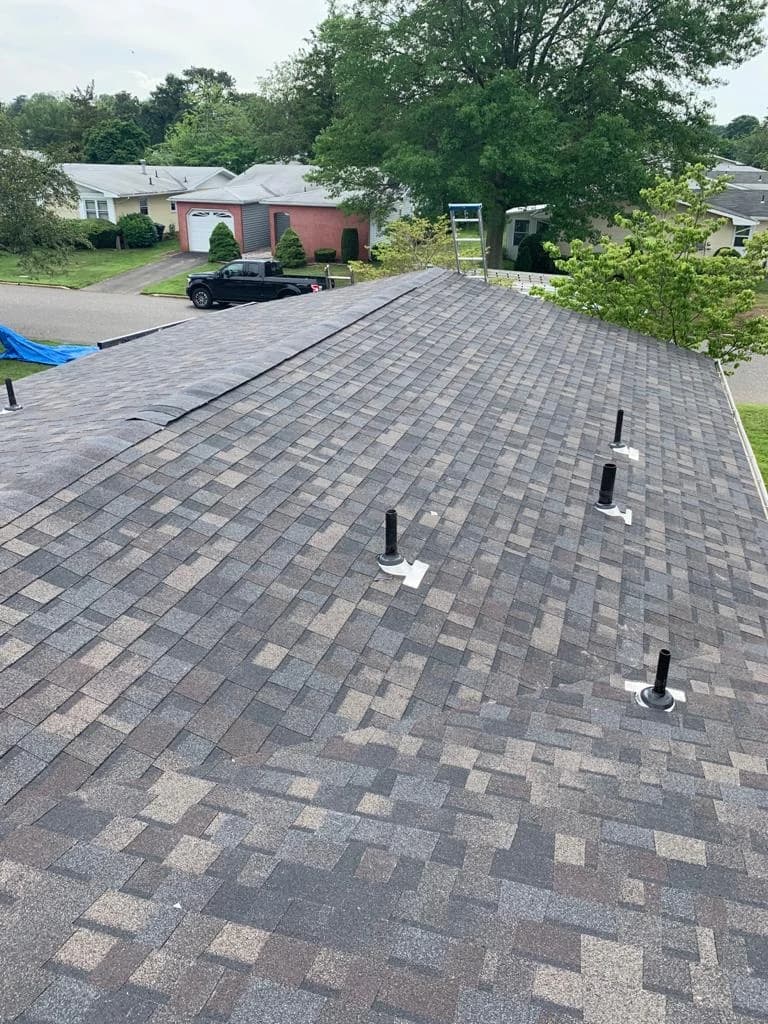 Gray shingle roof with capped ridge and individual pipe flashing bases