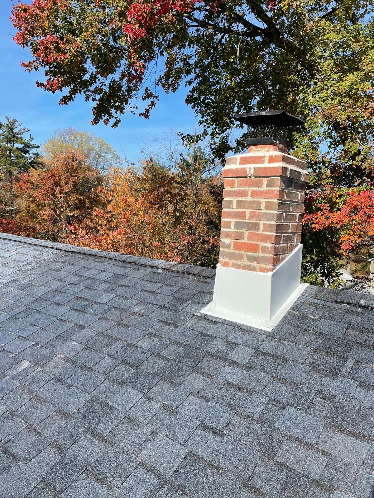 Red-brick chimney with dark screened cap and white roof flashing
