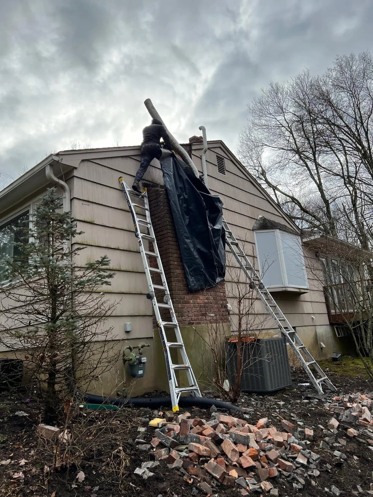 Chimney masonry removal and flexible liner handling beside ladders and protective sheeting