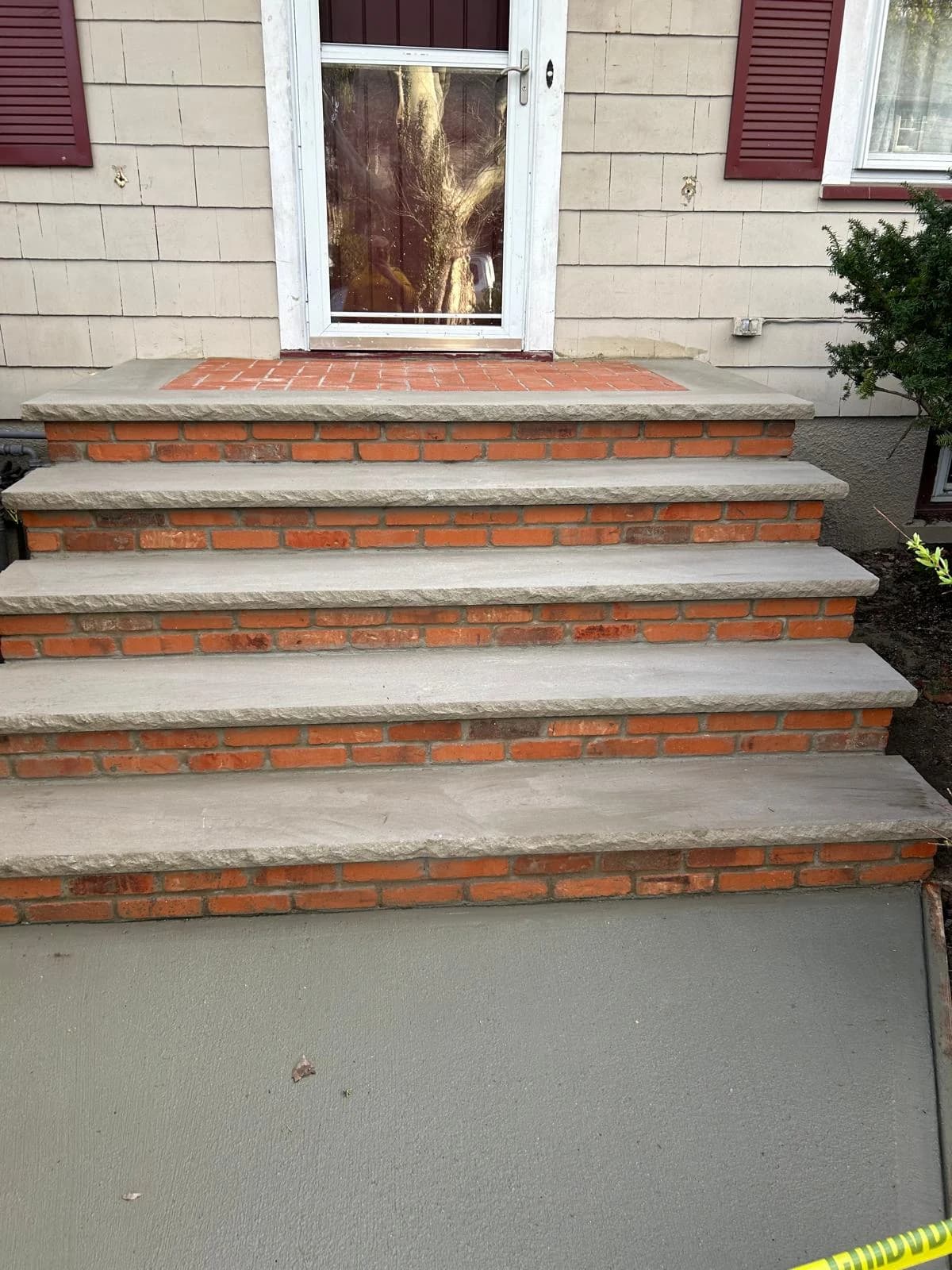Close view of the gray tread edges and brick landing at the front entrance